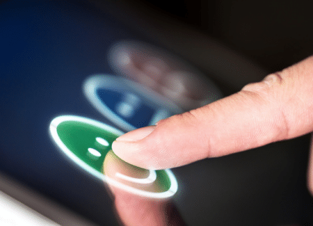 Ein Finger wählt einen grünen Emoticon auf einem Touchpad aus